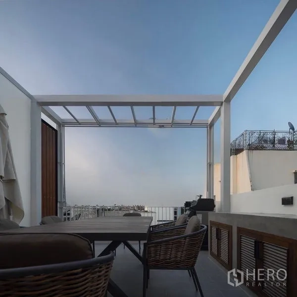 Townhouse for rent - Rooftop terrace with pergola, outdoor dining set, and open sky backdrop.