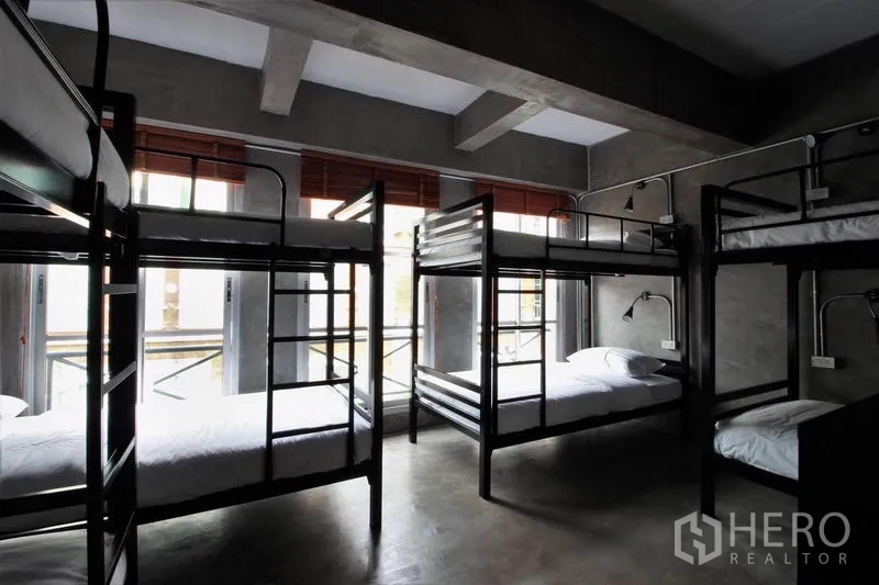 办公空间 出租或出售在Bang Rak, Bangkok - 上下铺卧室，清水混凝土墙与红色百叶窗。