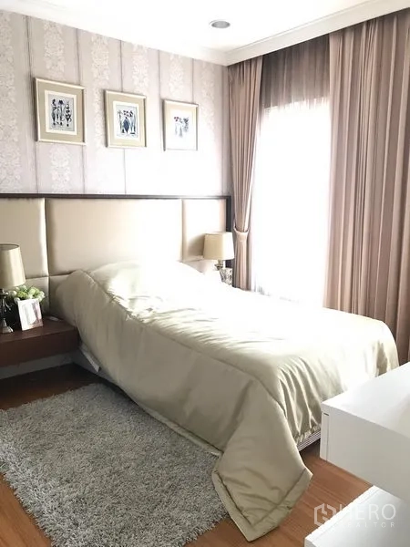 Townhouse for rent or sale in Bang Kho Laem, Bangkok - Balcony with artificial grass and two sun loungers behind sliding doors, black railings and treetop views.