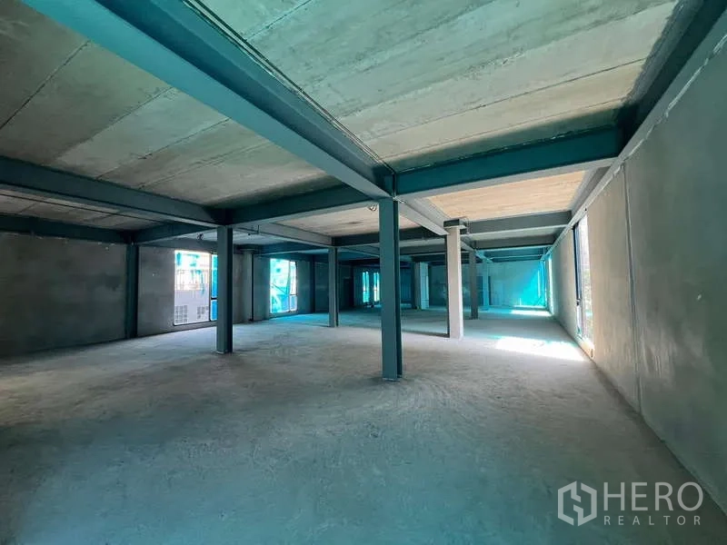 零售空间 出租在Pathum Wan, Bangkok - 大面积毛坯楼层，混凝土地面，多根承重柱与周边玻璃窗。