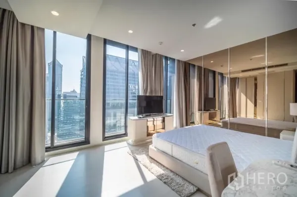 Condominium for rent in Pathum Wan, Bangkok - Bright master bedroom with floor-to-ceiling windows, city skyline view, TV console and mirrored wall.