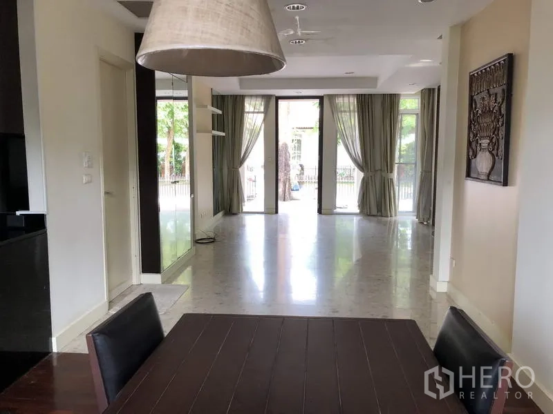 บ้าน ขายในWang Thonglang, Bangkok - โถงรับแขกแบบเปิดโล่งสว่าง มีประตูกระจกบานใหญ่ ผ้าม่าน และพื้นกระเบื้องเงา.