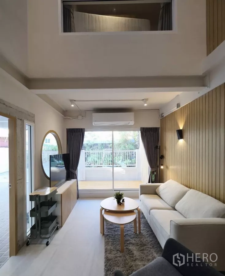 联排别墅 出租或出售在Watthana, Bangkok - 挑高客厅，沙发与电视柜，推拉门通向露台。