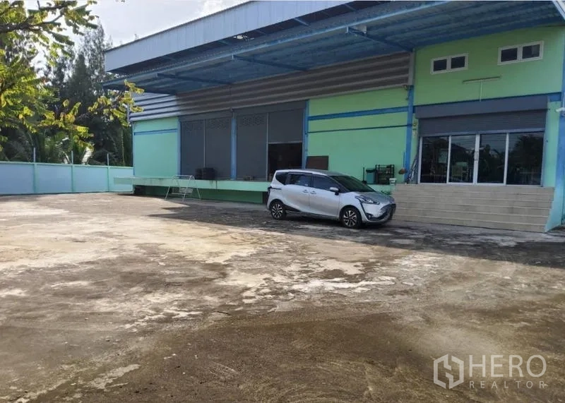 Warehouse for sale in Mueang Nonthaburi, Nonthaburi - Warehouse exterior with loading dock, roller shutters and a wide concrete yard.