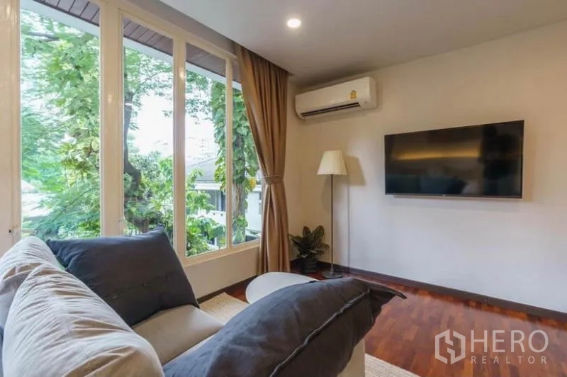 ทาวน์เฮาส์ ให้เช่าในKhlong Toei, Bangkok - ห้องนั่งเล่นดูทีวีอบอุ่น ทีวีติดผนัง หน้าต่างบานใหญ่ ม่าน และพื้นไม้