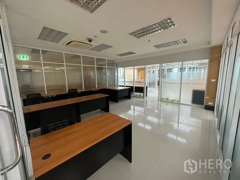 办公空间 出租在Suan Luang, Bangkok - 带桌椅的私密会议室，玻璃墙与推拉门，亮面瓷砖地面与吊顶空调。