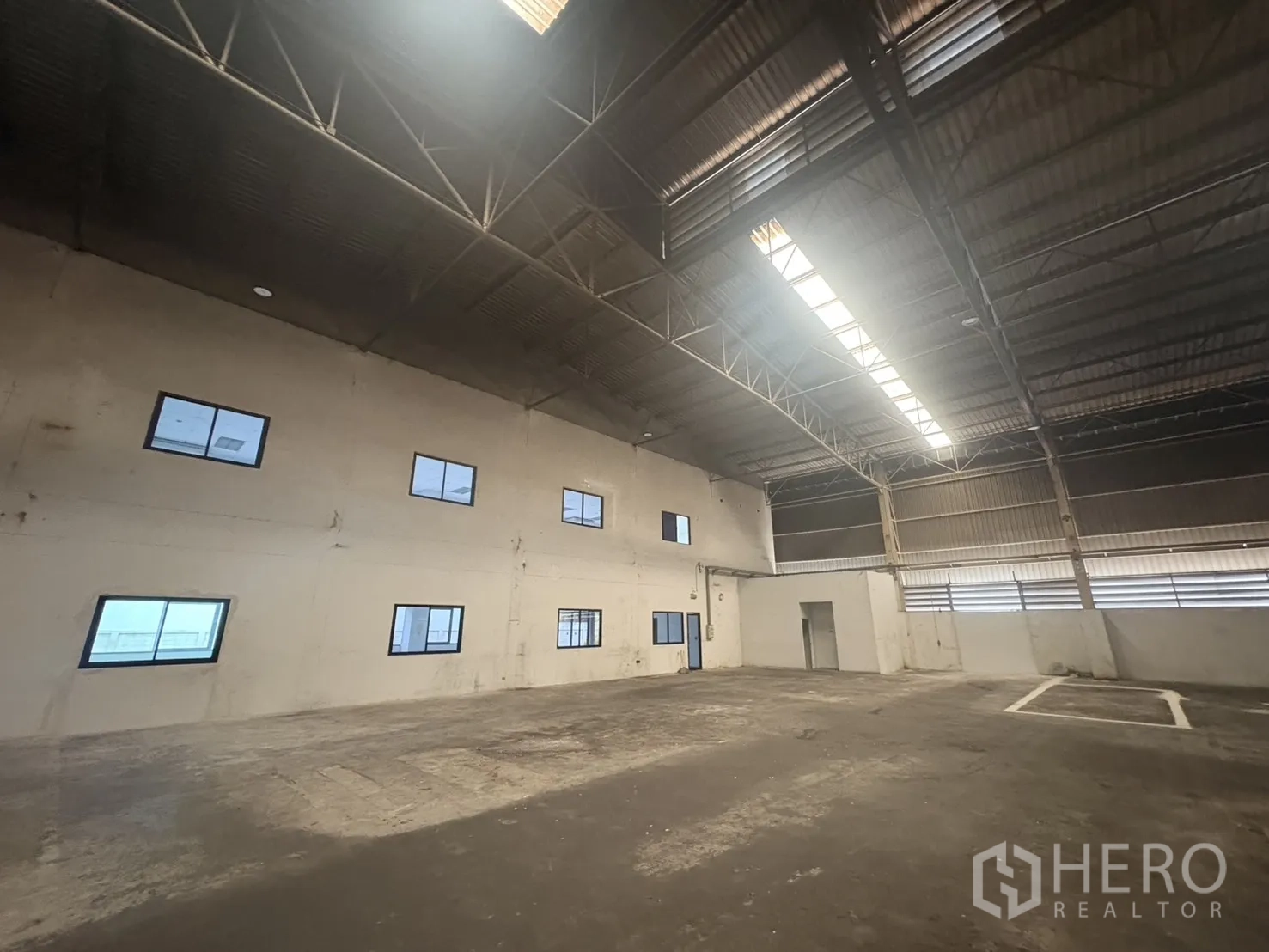 Factory for rent or sale in Samut Prakan - Open‑plan office with white tiles, air‑conditioning units and rows of windows.
