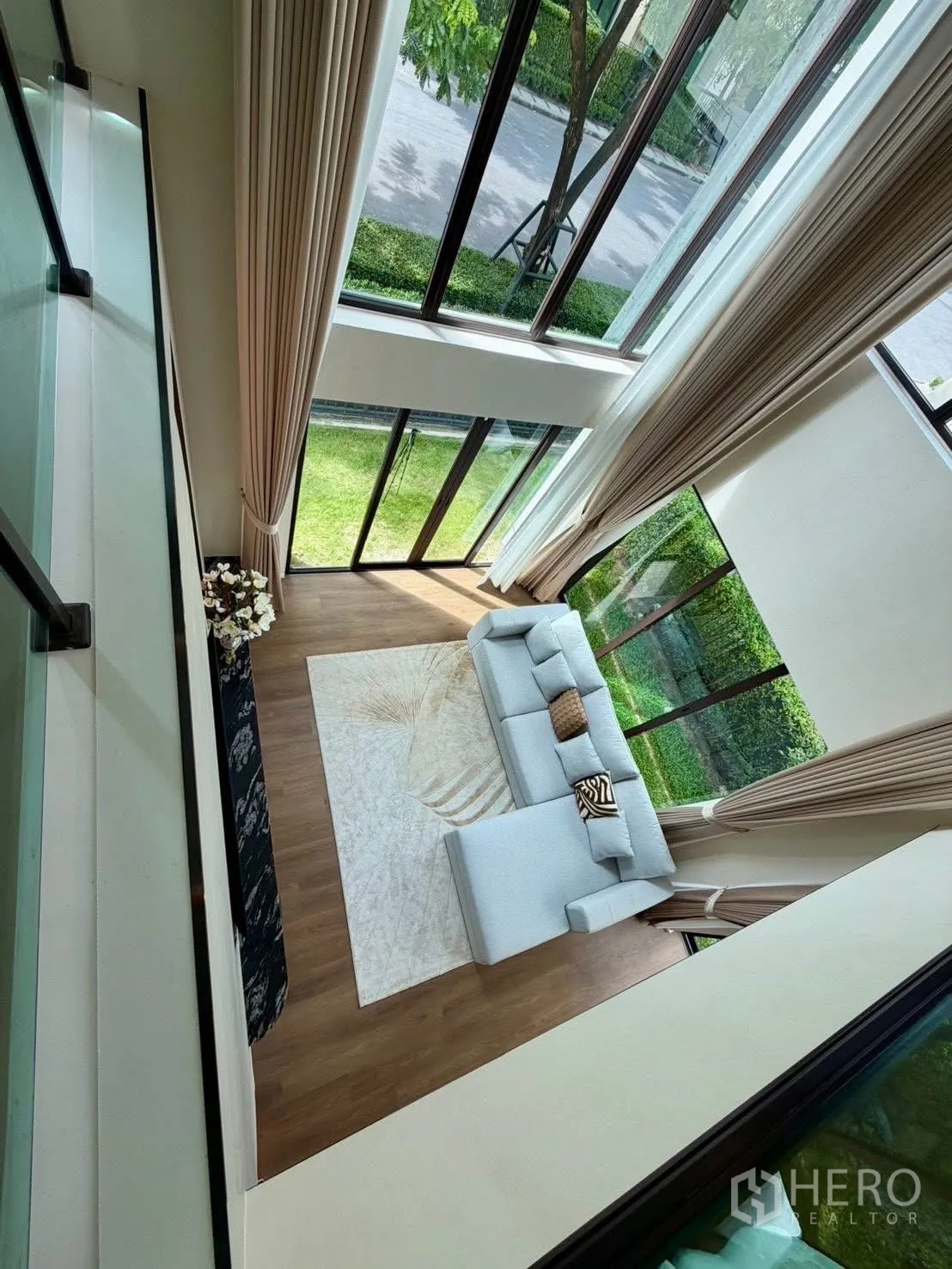 Detached House for rent in Bang Phli, Samut Prakan - Double-height living room with floor-to-ceiling windows, L-shaped sofa and garden view.