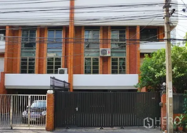 Townhouse for rent in Pathum Wan, Bangkok - Gated brick townhouse facade with tall windows and parking entry.