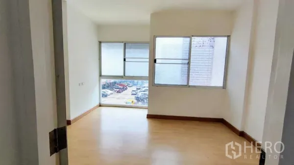 Townhouse for sale in Bang Khen, Bangkok - Upper-floor room with large windows bringing natural light and views over a parking area.