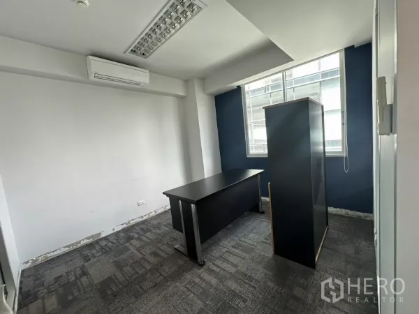 Office Space for rent in Watthana, Bangkok - Compact manager’s office featuring a blue feature wall, carpet tiles and natural light from the window.