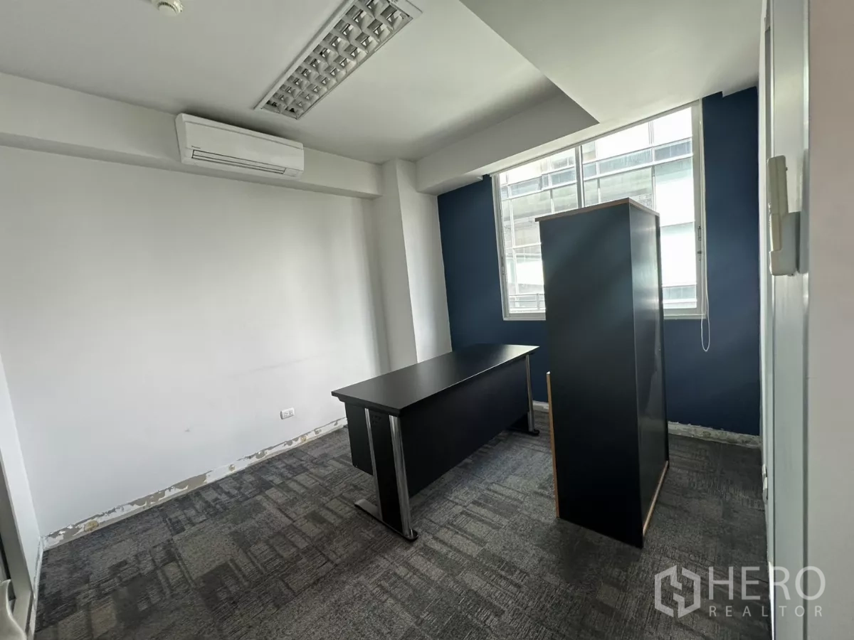 Office Space for rent in Watthana, Bangkok - Compact manager’s office featuring a blue feature wall, carpet tiles and natural light from the window.