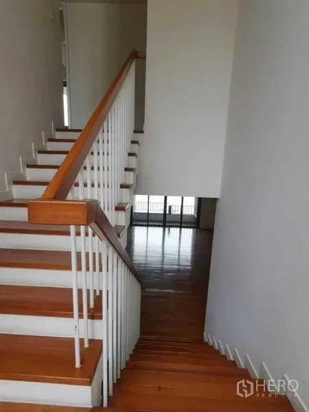 公寓 出租在Yan Nawa, Bangkok - 复式公寓内的木质楼梯与白色栏杆，通向明亮客厅。