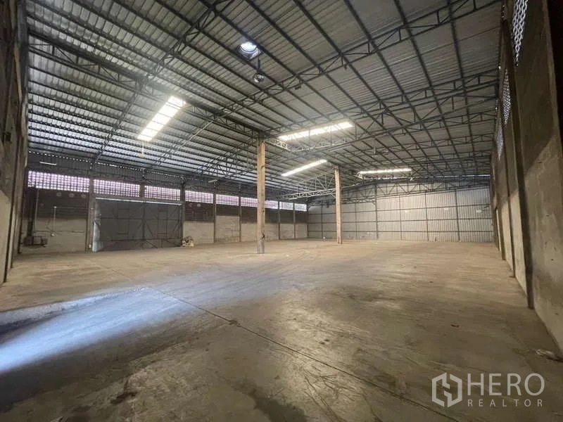 Warehouse for rent in Rat Burana, Bangkok - Open-plan storage hall with wide shutter doors, ventilation blocks and tall clear height for racking and forklift movement.