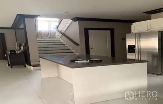 Detached House for sale in Bang Phli, Samut Prakan - Sleek kitchen island next to the staircase with a bright foyer leading to the upper floor.