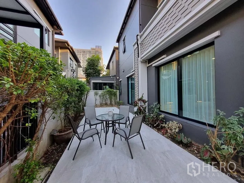 Detached House for rent in Bang Khae, Bangkok - Outdoor patio with round glass table and four chairs between two buildings.