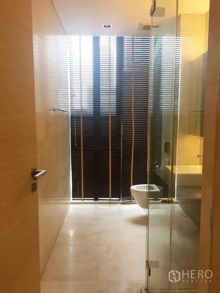 Condominium for rent in Bang Rak, Bangkok - Glass-enclosed shower area with window blinds and neutral tile finishes.