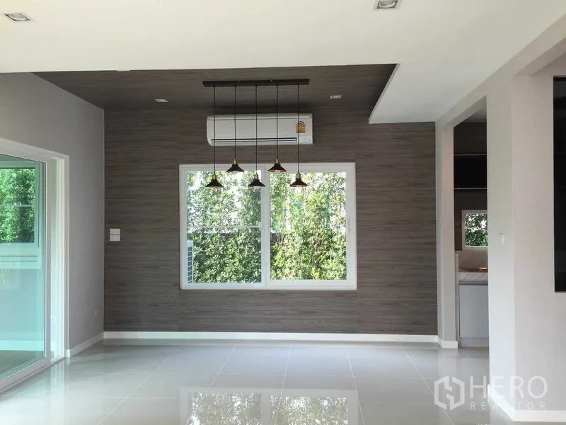 Townhouse for sale in Bang Khae, Bangkok - Dining zone with cluster pendant lights, large window facing green hedges and entry to kitchen.