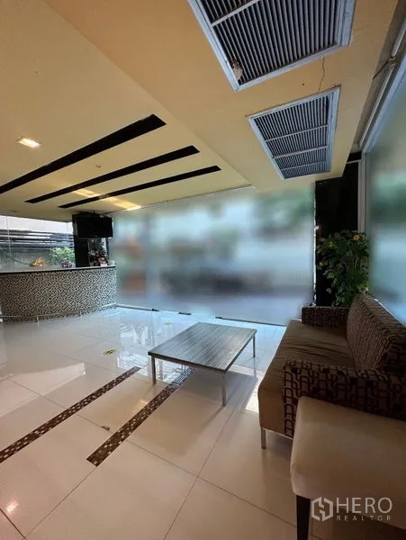 Apartment for rent in Khlong Toei, Bangkok - Lobby with reception counter, sofa seating and wide windows.