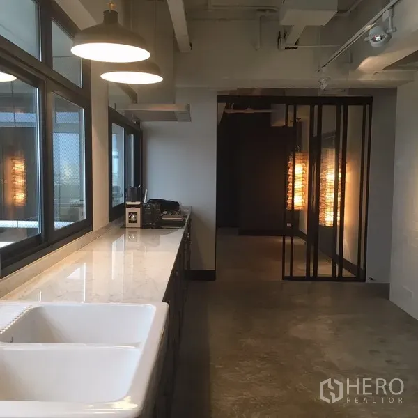 คอนโด ให้เช่าในWatthana, Bangkok - ครัวสไตล์ลอฟท์ เคาน์เตอร์หินอ่อนยาว อ่างล้างคู่ โคมไฟแขวน และหน้าต่างบานใหญ่.