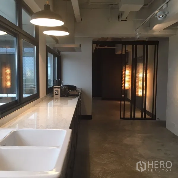 คอนโด ให้เช่าในWatthana, Bangkok - ครัวสไตล์ลอฟท์ เคาน์เตอร์หินอ่อนยาว อ่างล้างคู่ โคมไฟแขวน และหน้าต่างบานใหญ่.