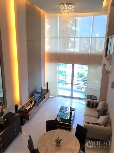 Condominium for rent in Pathum Wan, Bangkok - Floor-to-ceiling windows with chandelier brighten the lounge opening to a balcony with city views.