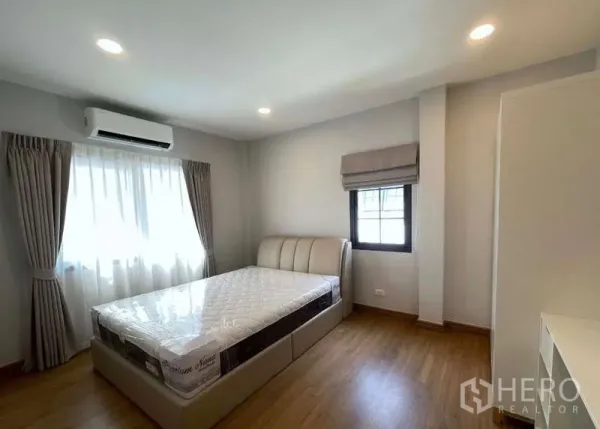 Detached House for rent in Bang Phli, Samut Prakan - Bright bedroom with air conditioner, bed and soft drapes over wood floors