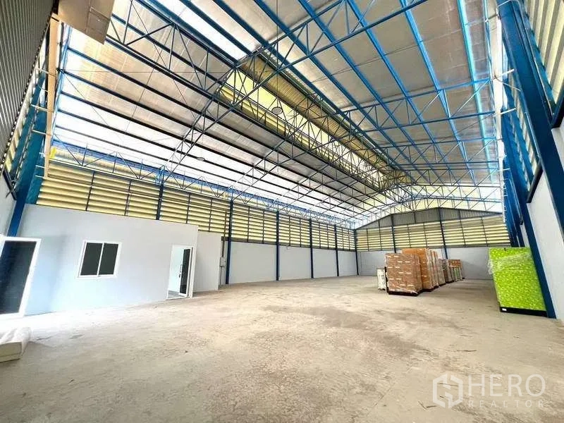 Warehouse for rent in Lat Lum Kaeo, Pathum Thani - High-ceiling warehouse with skylights and blue steel trusses for natural light.