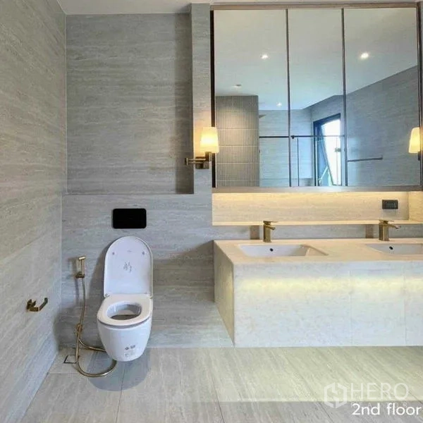 Detached House for rent in Bang Kapi, Bangkok - Spacious bathroom with twin basins, backlit mirror and neutral stone tiles.