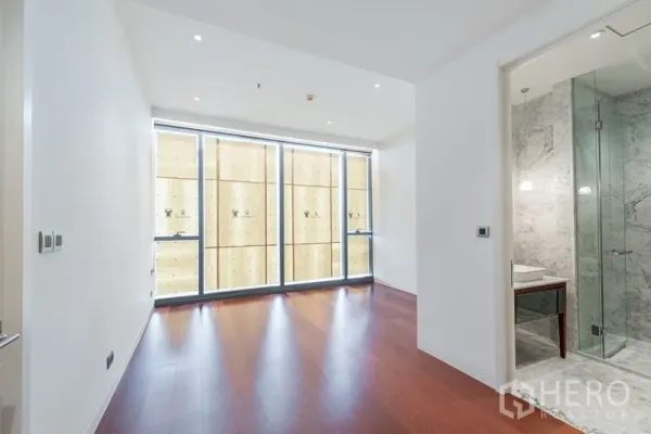 คอนโด ขายในWatthana, Bangkok - ห้องนอนสว่างพร้อมหน้าต่างเต็มผนัง พื้นไม้สวย และห้องน้ำหินอ่อนพร้อมตู้ฝักบัวกระจกในย่านทองหล่อ วัฒนา