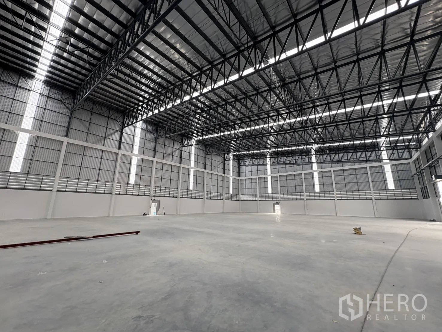 Factory for rent in Bang Pakong, Chachoengsao - Spacious high-bay warehouse interior with steel trusses and polished concrete floor.