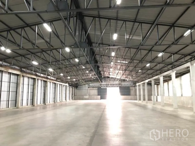 Warehouse for rent in Pak Kret, Nonthaburi - Long view of the warehouse aisle with steel trusses, LED lighting and wide truck-friendly loading access.
