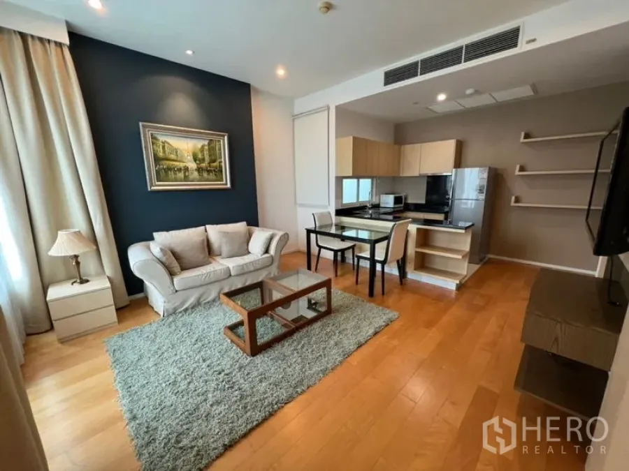 คอนโด ให้เช่าในChatuchak, Bangkok - ห้องนั่งเล่นสว่างพร้อมโซฟา โต๊ะกระจก พรม และครัวเปิดพื้นไม้