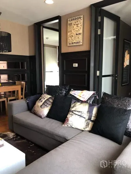Condominium for rent in Pathum Wan, Bangkok - Living area with gray sofa, dining nook and doors leading toward the kitchen.