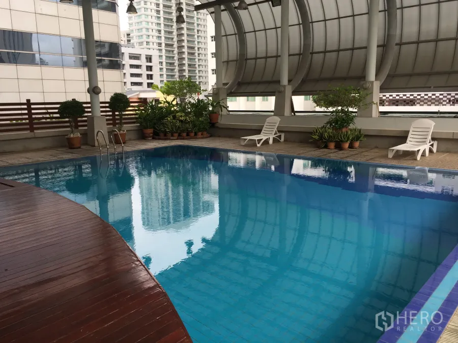 คอนโด ให้เช่าหรือขายในWatthana, Bangkok - สระว่ายน้ำกึ่งในร่มของคอนโด พื้นไม้ เก้าอี้อาบแดด และกระถางต้นไม้ ท่ามกลางวิวเมือง