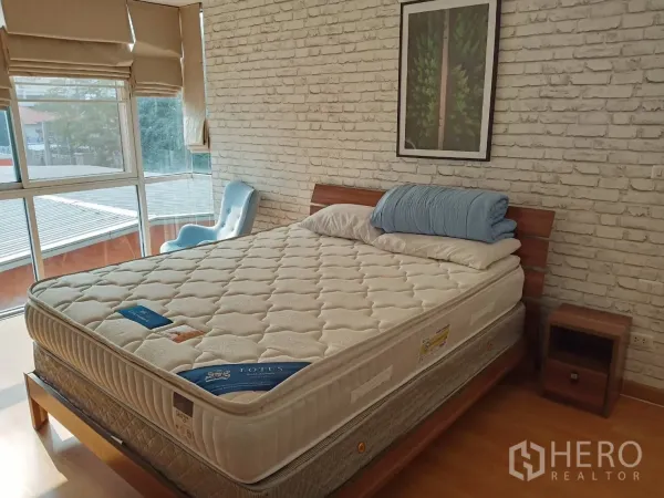 คอนโด ให้เช่าหรือขายในKhlong Toei, Bangkok - ห้องนอนมุมสว่าง หน้าต่างบานใหญ่ ผนังอิฐ พร้อมโต๊ะข้างเตียง