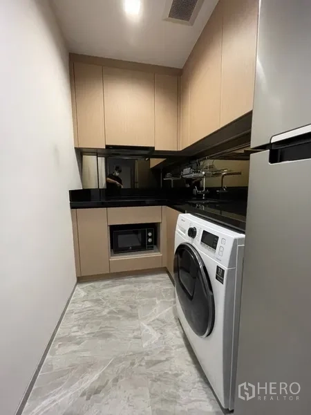 公寓 出租在Watthana, Bangkok - 走廊式厨房，配冰箱、洗衣机、微波炉与收纳柜。
