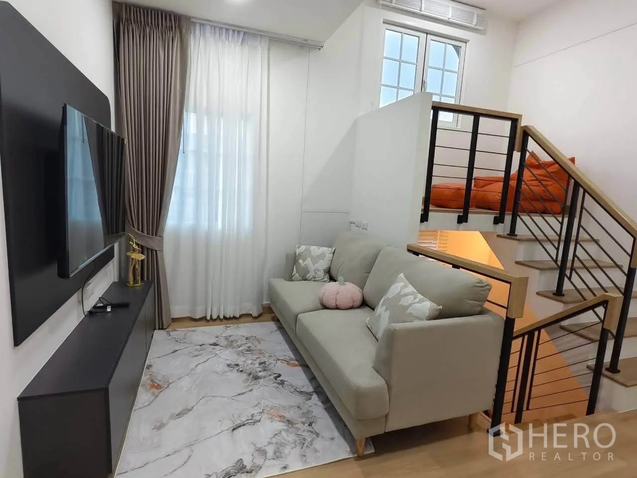Detached House for rent in Bang Phli, Samut Prakan - TV lounge with sofa, wall-mounted television and stairs with metal railing.