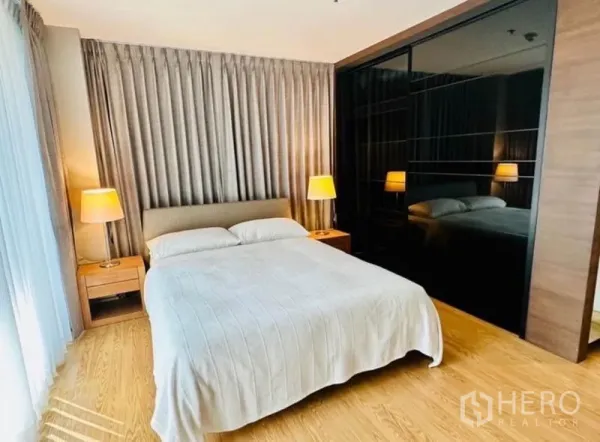 Condominium for rent in Watthana, Bangkok - Cozy master bedroom with queen bed, bedside lamps and mirrored wardrobe.