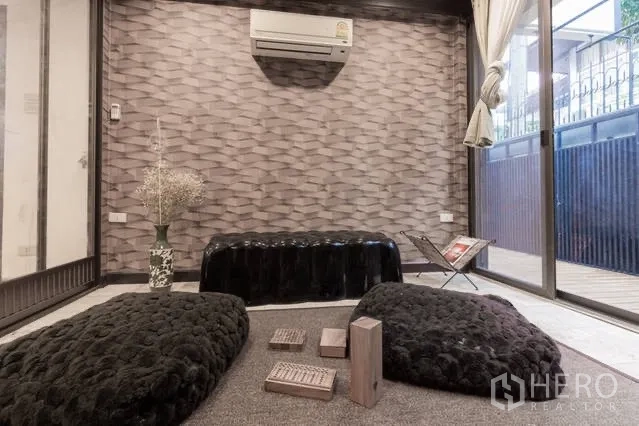 บ้าน ให้เช่าในWatthana, Bangkok - มุมนั่งเล่นบรรยากาศอบอุ่น ผนังลายสามมิติ เบาะนั่งพื้น และประตูกระจกบานเลื่อน