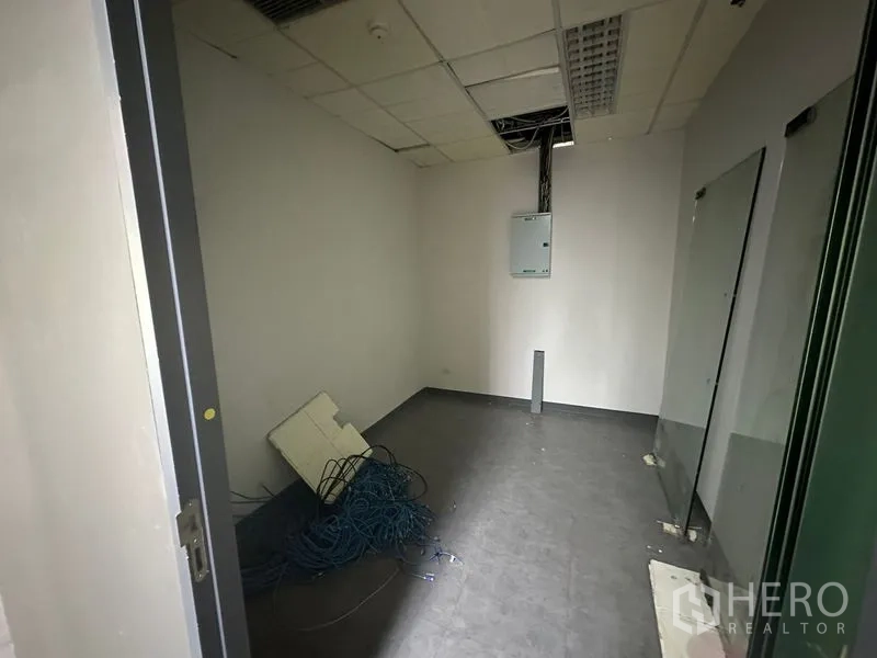 Office Space for rent - Small IT or server room with electrical panel, exposed cabling and dark floor.