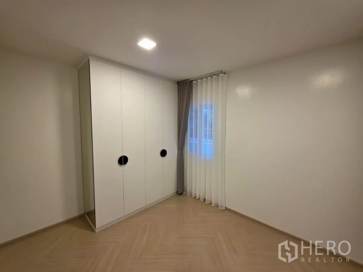 Detached House for rent in Bang Phli, Samut Prakan - Empty room with built-in white wardrobe and corner window.