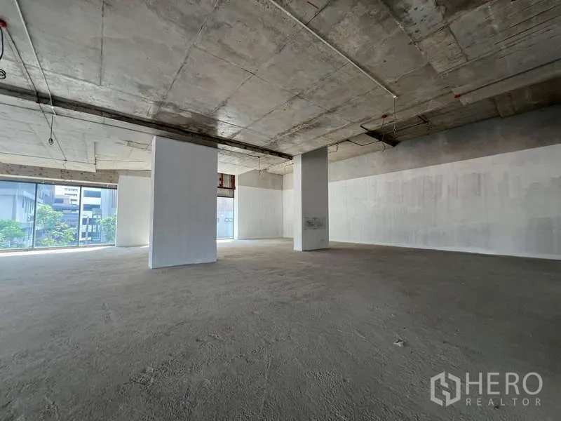 零售空间 出租 - 宽敞未装修的商铺内部，结构柱与高挑层高，转角大窗，适合二次装修。