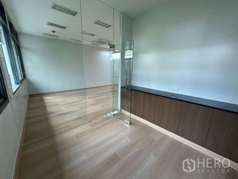Office Space for rent - Glass-partitioned meeting room with wood floors and built-in storage cabinets.