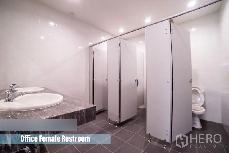 Detached House for rent in Khlong Toei, Bangkok - Clean restroom with multiple stalls, tiled walls and twin sinks.