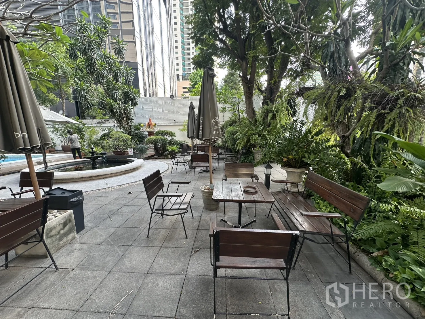 Retail Space for rent in Watthana, Bangkok - Leafy outdoor terrace with wooden tables, umbrellas, and a circular water feature beside the garden.