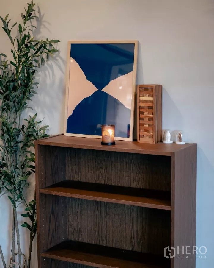 独立式住宅 出租或出售在Bang Phli, Samut Prakan - 木书架特写，摆放装饰画与蜡烛。