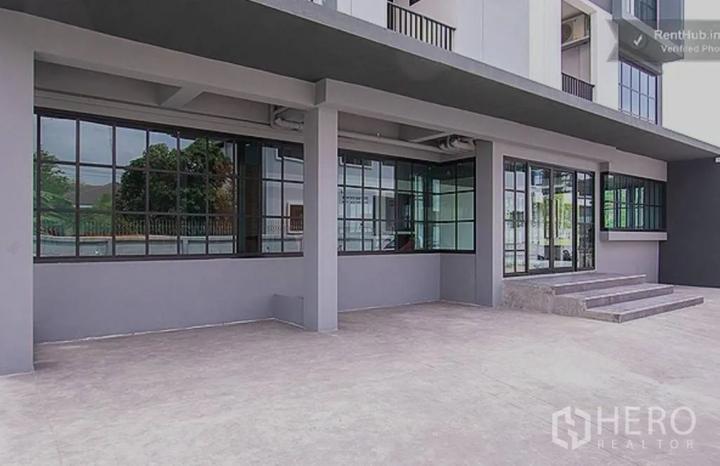 Apartment for rent in Phra Khanong, Bangkok - Ground-floor entrance with wide paved area and glass facade.