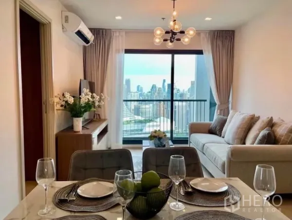 Condominium for rent in Pathum Wan, Bangkok - Dining setup for four facing a bright lounge and balcony with Bangkok skyline.