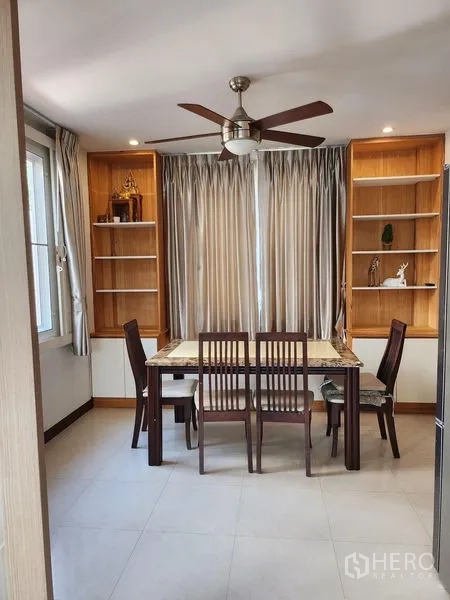 Detached House for rent in Bang Kapi, Bangkok - Dining area with ceiling fan, four-seat table and built-in wooden shelving.